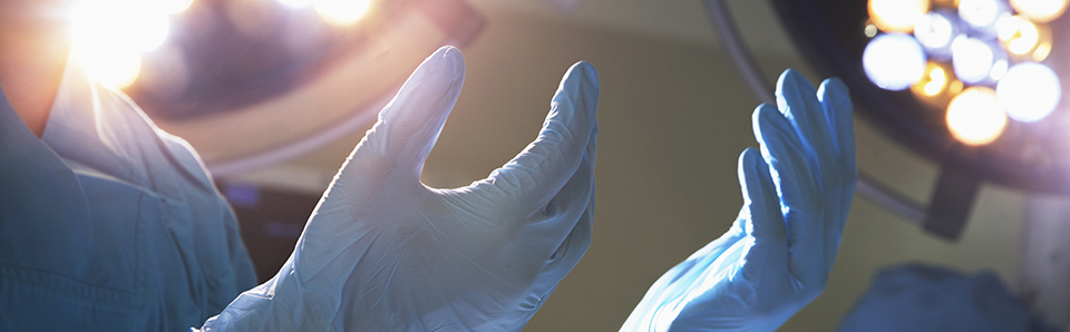 Doctor holding his hands up with surgical gloves