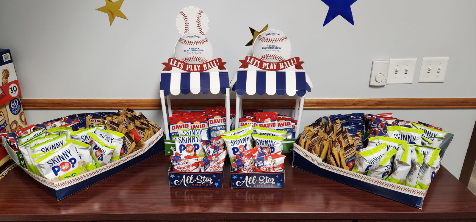 A table full of small bags of pretzels, sunflower seeds, popcorn and crackerjacks