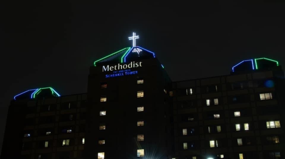 The outside of Methodist all lit up in just blue, white and green lines
