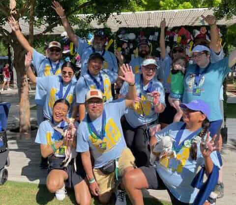 Magdaleno Jacquez III and a group of people in matching shirts and hats all cheering